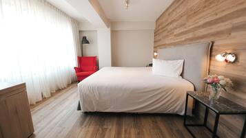 Una habitación de hotel con una cama grande, una silla roja, un escritorio y una pared de acento de madera.