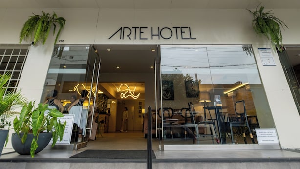 L’entrée de l’hôtel ARTE se distingue par sa façade moderne, ses grandes fenêtres et un escalier menant à l’entrée.