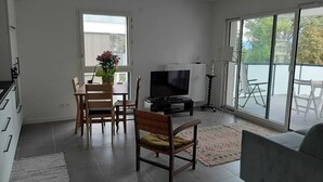 A modern living room with a TV, seating, and a balcony.