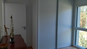 A room with a wooden desk, a door, and a large window.
