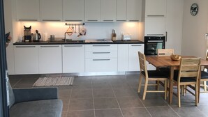 A modern kitchen with white cabinets, a black countertop, and a dining area with wooden chairs and a table.