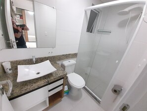 A bathroom with a white sink, toilet, and glass-enclosed shower.