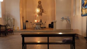 Ein Kircheninneres mit einem zentralen Altar, Kirchenbänken und einer Statue.