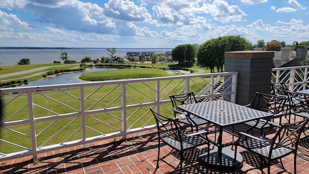 A patio with a table and chairs overlooking a landscaped area with a pond and a view of the water. - Kingsmill Condo on Golf Course 9th Fairway! Local owner (Williamsburg)