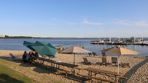 A beach with picnic tables and umbrellas, a marina in the background, and a clear sky. - Kingsmill Condo on Golf Course 9th Fairway! Local owner (Williamsburg)