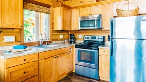 A kitchen with wooden cabinets, a stainless steel refrigerator, a microwave, and a stove.