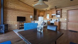 A cozy cabin interior with a dining area, kitchen, and a television.
