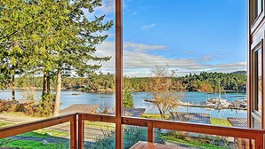 A wooden deck with a view of a lake and marina. - Snug Harbor Resort and Marina - Two Bedroom Water View Cabin, Queen Beds (Friday Harbor)