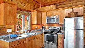 Una cocina con armarios de madera, un refrigerador de acero inoxidable, un microondas y un horno.