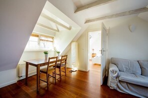 Cozy living area with a dining space, sofa, and exposed wooden beams.