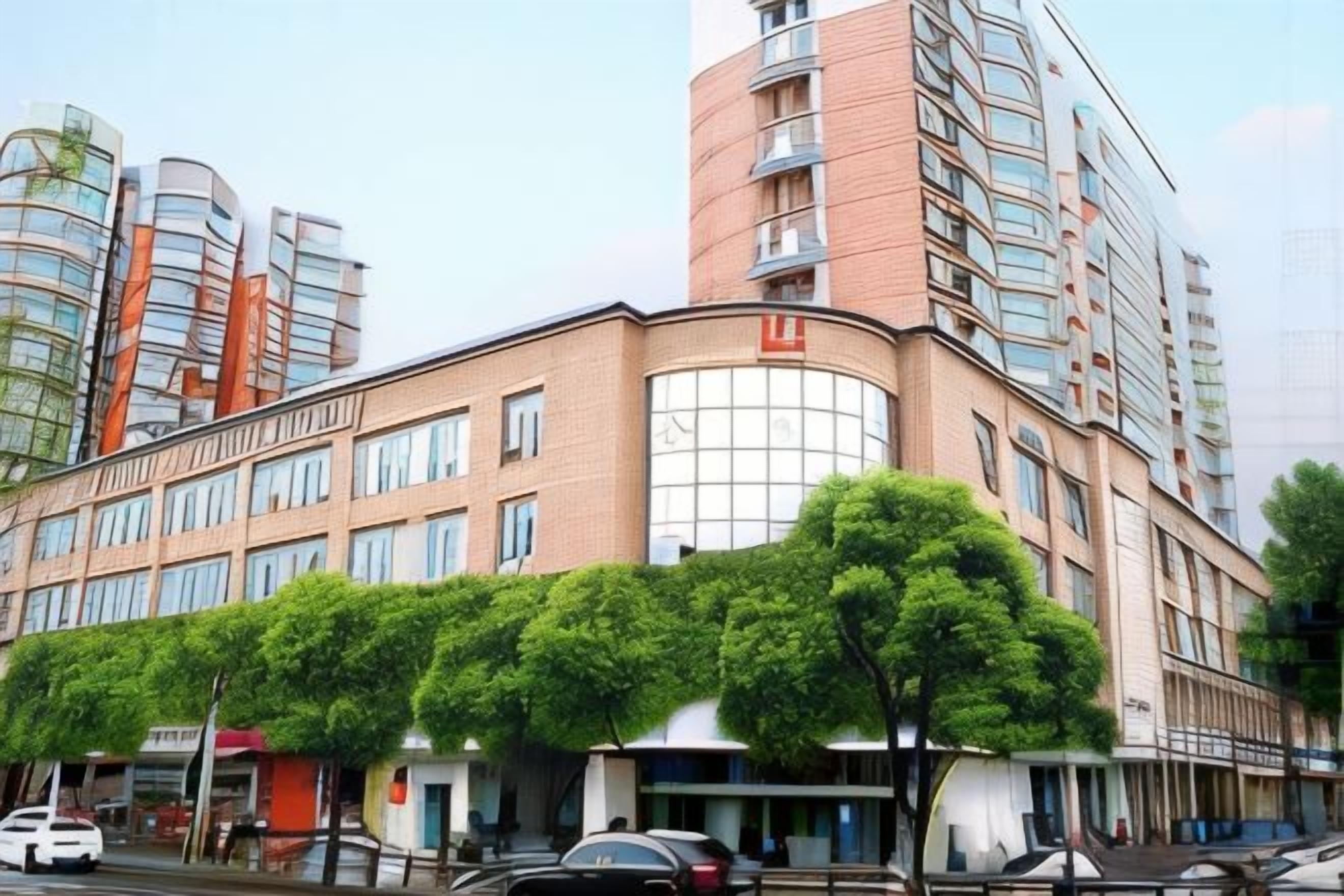 A multi-story hotel with a curved facade, large windows, and a central entrance.