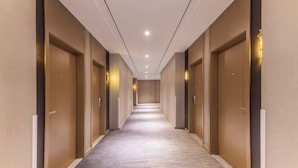 A long, narrow hotel corridor with wooden doors on both sides and a carpeted floor. - Jinjiang Inn (Wujiang Zhongshan North Road Pedestrian Street) (Suzhou)