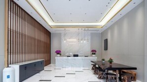 A modern reception area with a marble counter, wooden slatted wall, and a dining table with stools. - Jinjiang Inn (Wujiang Zhongshan North Road Pedestrian Street) (Suzhou)