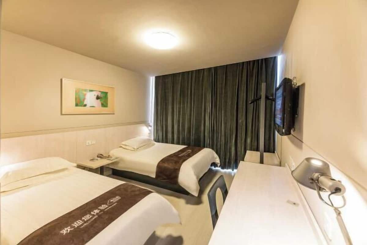 A hotel room with two beds, a desk, a TV mounted on the wall, and a painting on the wall.