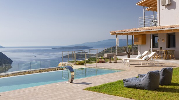 Uma villa moderna com piscina, área de estar externa e vista para o mar.