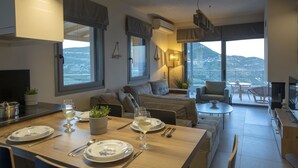 Uma sala de estar moderna com área de jantar, janelas amplas e vista para as montanhas.