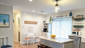 Uma cozinha com ilha central, armários brancos e uma placa com a palavra SAVANNAH.