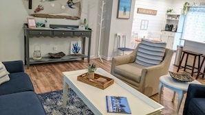 Sala de estar com sofá, poltrona, mesa de centro e parede decorada com tema náutico.