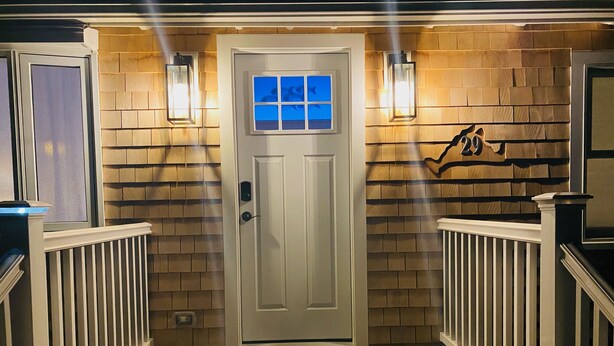 A wooden-floored entryway with a white door, two wall-mounted lights, and a small window above the door. - LOCATION  & QUALITY! Right in town, freshly renovated, near everything u need! (Tisbury)
