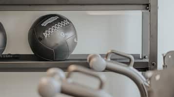 Un gimnasio con equipo de ejercicio y un balón deportivo negro que dice "Technogym" y "9kg".