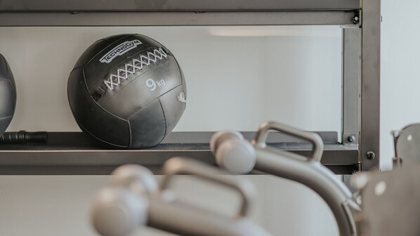 Un gimnasio con equipo de ejercicio y un balón deportivo negro que dice "Technogym" y "9kg".
