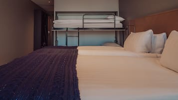 A hotel room with a bunk bed, a single bed, and a patterned blanket.