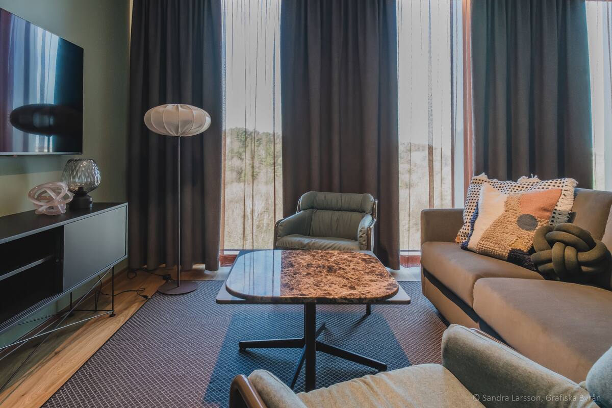 Een moderne woonkamer met een flatscreen televisie, een bank, een salontafel en een vloerlamp.