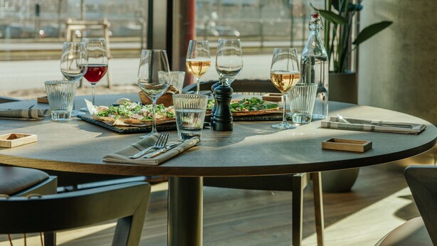 A round dining table with a meal, glasses, and a bottle.