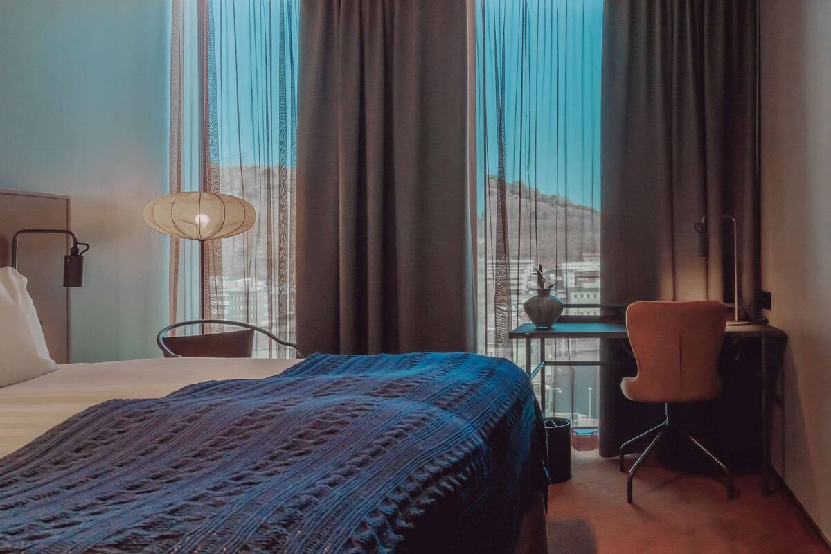 Een hotelkamer met een bed, een bureau, een stoel, een lamp en een televisie.