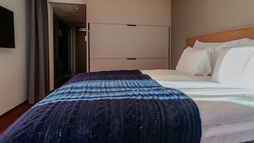 Una habitación de hotel con cama, armario y puerta que da a un pasillo.
