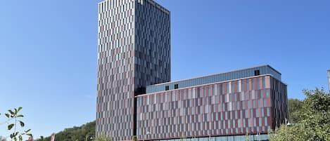 A modern hotel with a tall, rectangular tower and a shorter building with a grid-like facade.