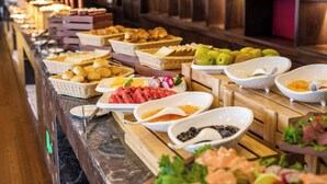 Un bufé con diversas opciones de comida, incluyendo frutas, pasteles y mariscos.