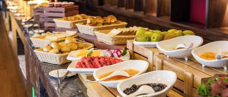 A buffet with various food items including fruits, pastries, and seafood.
