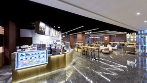 Eine moderne Hotelhalle mit Rezeption, Sitzgelegenheiten und einer Speisenauslage.