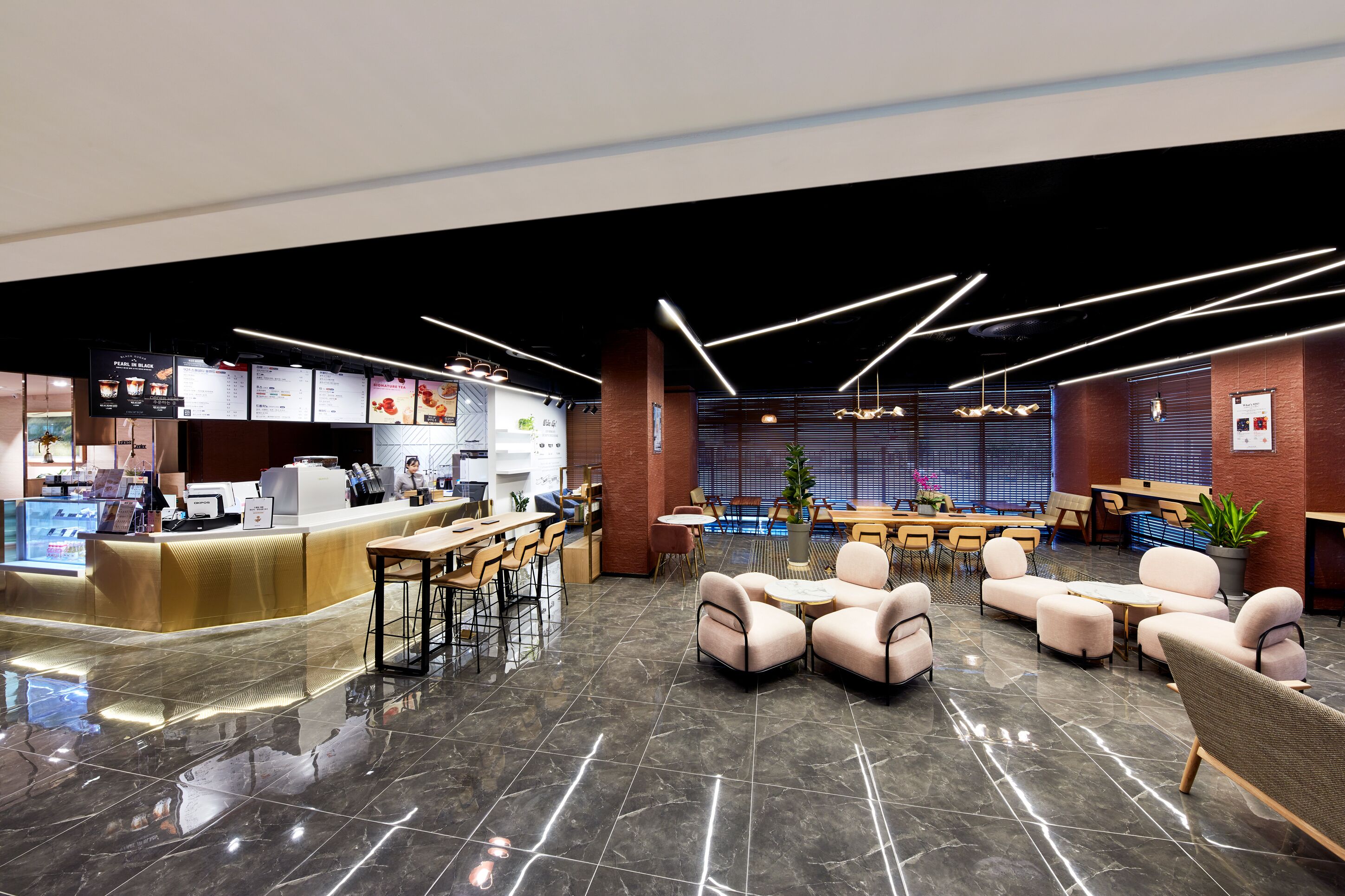 A modern interior with a reception desk, seating area, and a dining space.