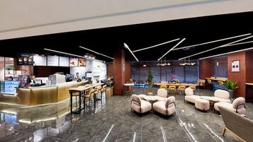 A modern interior with a reception desk, seating area, and a dining space.