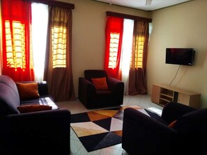 Relax in this stylish living room with a sofa set, armchair, and ottoman, plus a flat-screen TV and storage cabinet.