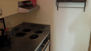 Una cocina compacta con estufa, horno y un pequeño estante con cestas.