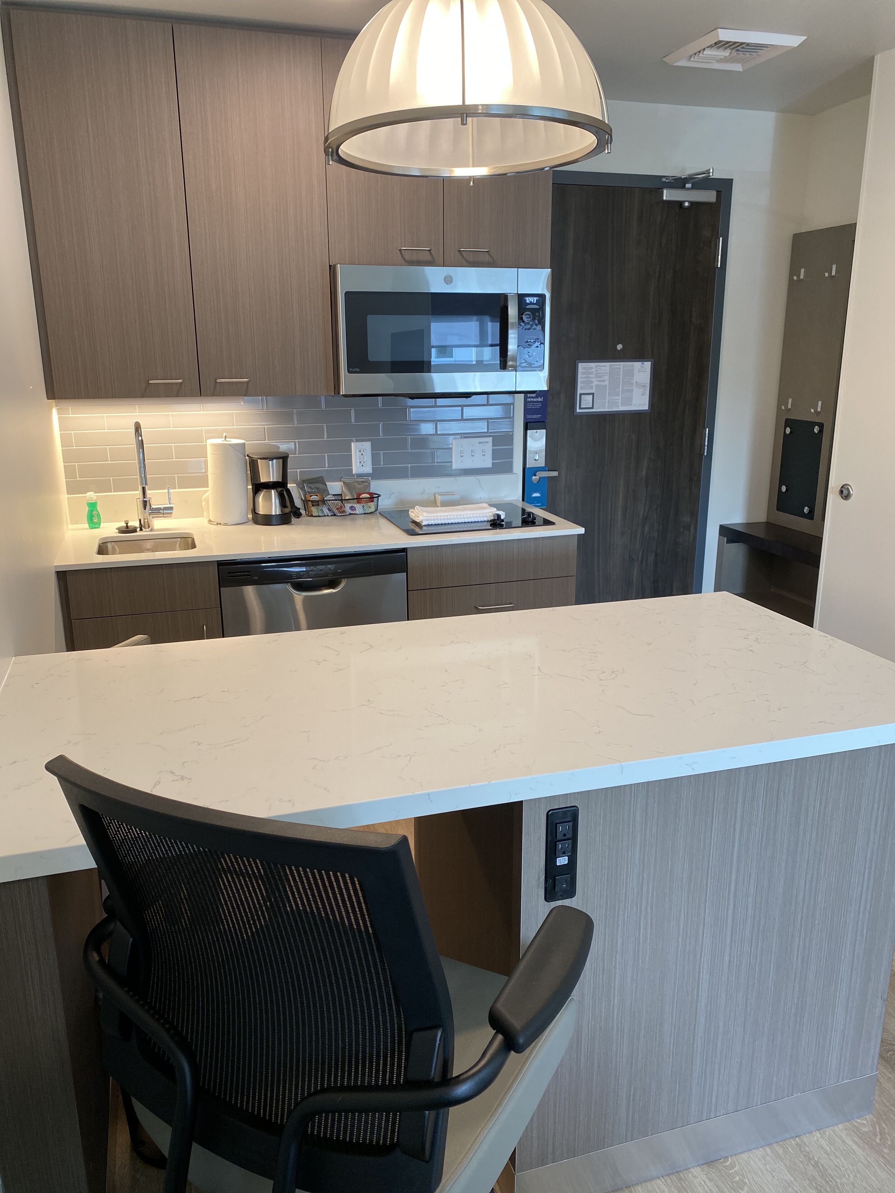 A modern kitchen with a large island, stainless steel appliances, and a pendant light.