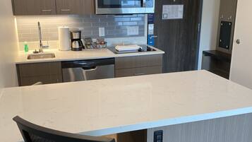 A modern kitchen with a large island, stainless steel appliances, and a pendant light.