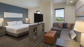 A hotel room with a bed, a TV, a sofa, and a desk.