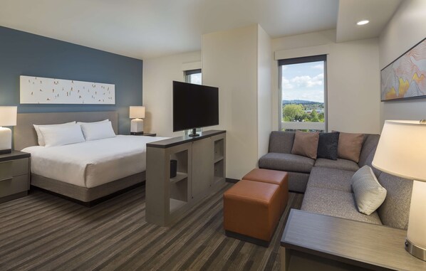 A hotel room with a bed, a TV, a sofa, and a desk.