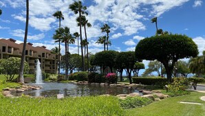 Un resort con un estanque, palmeras y un edificio con balcones.