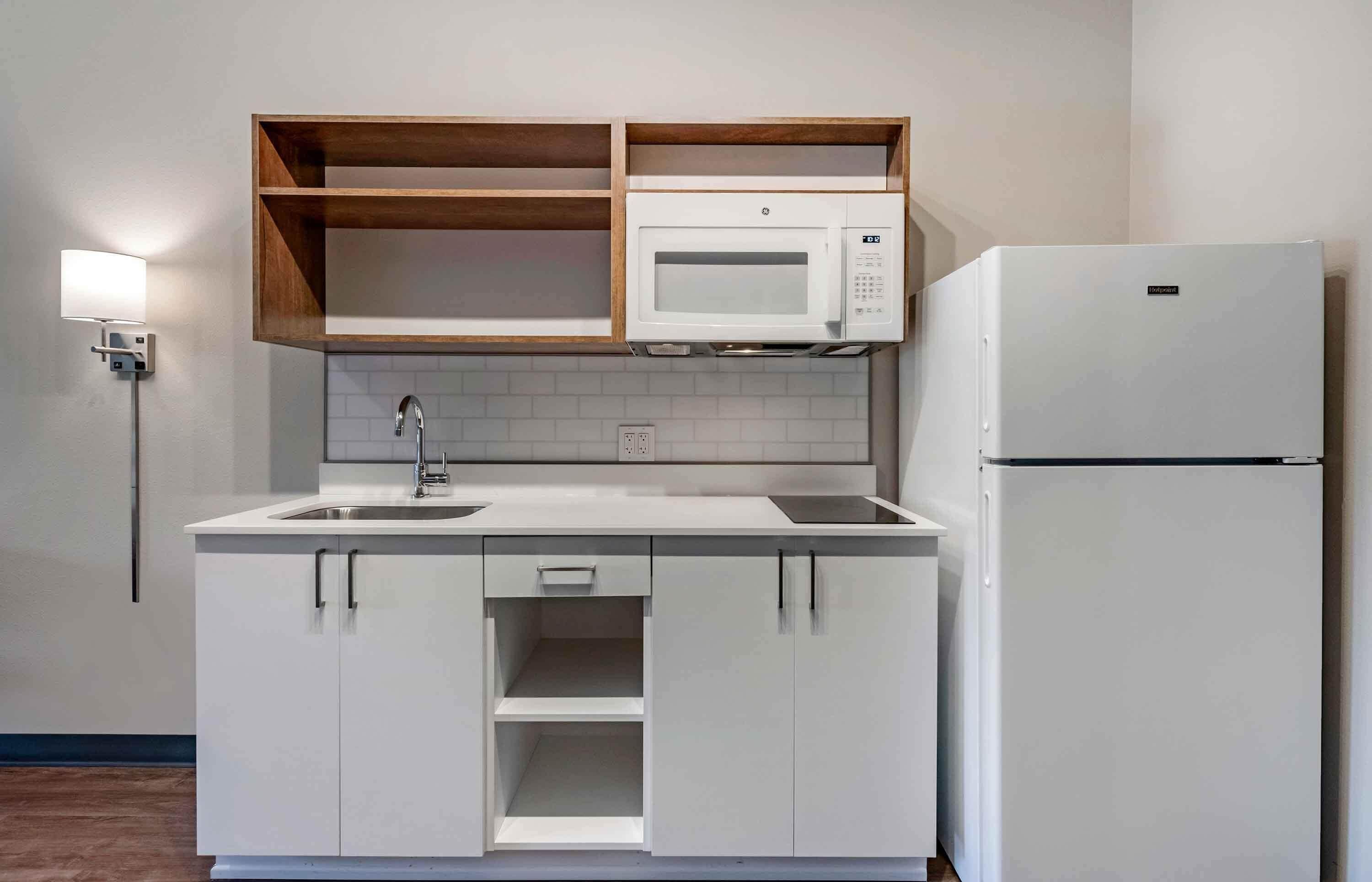 Eine kleine Küche mit eingebauter Mikrowelle, einem Kühlschrank und einem Spülbecken.