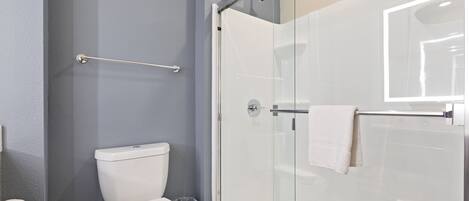 A bathroom with a glass-enclosed shower, a white toilet, and a towel rack.