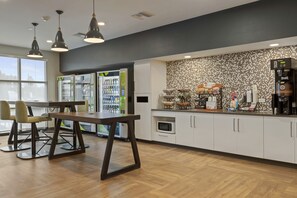 A modern kitchen area with a coffee machine, refrigerator, and seating area. - Extended Stay America Premier Suites Melbourne I95 (Melbourne)