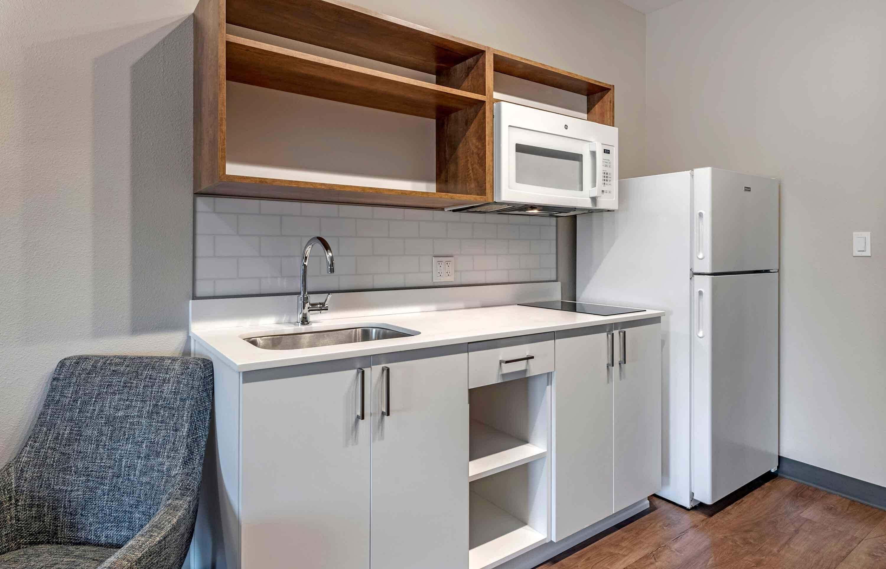 Una cocina compacta con microondas, refrigerador y pileta doble.