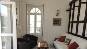 A living room with a sofa, a chair, a small table, and a window. - Gîte Rohan - Château du Parc Soubise (Mouchamps)