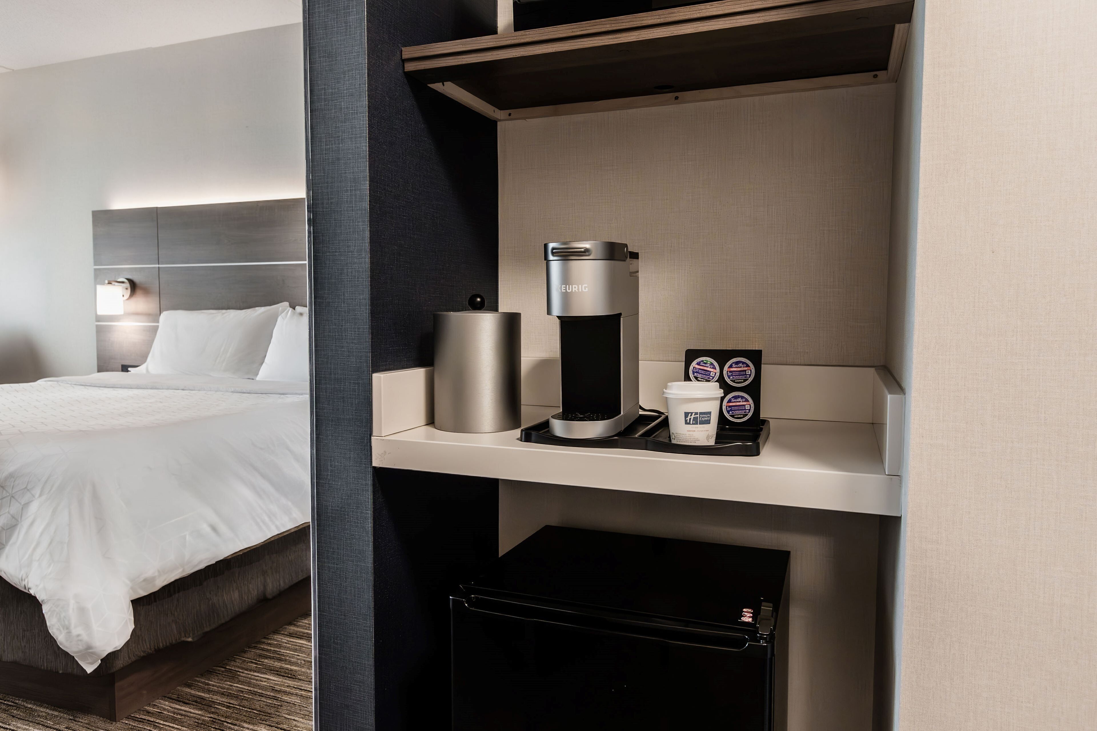 Ein Hotelzimmer mit Bett, einer Kaffeemaschine und einer Kaffeetasse auf einem Tablett.
