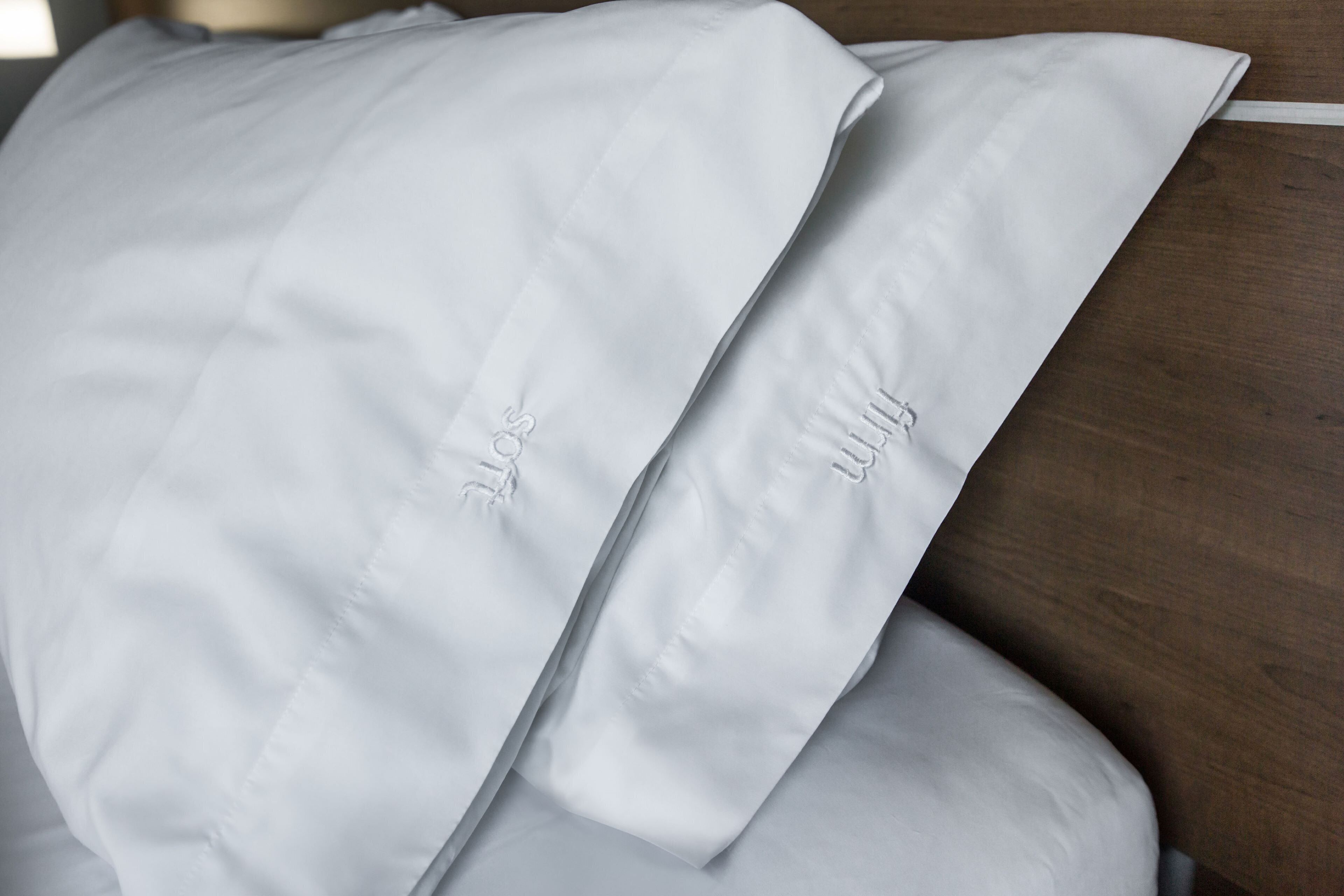 A neatly folded white pillow with embroidered text on a wooden surface.